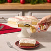 A hand sprinkles Mccormick Cranberry Finishing Sugar, 3.43 Oz onto a slice of frosted cake to add a festive touch of color and flavor.