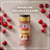 A bottle of Mccormick Cranberry Finishing Sugar, 3.43 Oz is centered on a marble surface surrounded by fresh and sugared cranberries under the text Shake On Holiday Flavor.