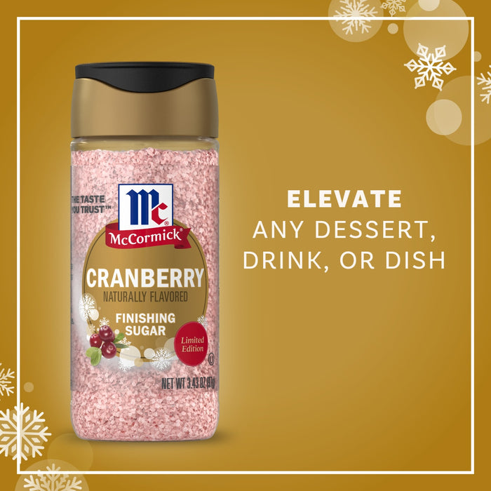 A bottle of Mccormick Cranberry Finishing Sugar, 3.43 Oz is displayed against a festive gold background with snowflakes to show how it can elevate any dessert, drink, or dish.