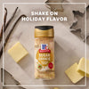 A bottle of Mccormick Sugar Cookie Finishing Sugar, 3.39 Oz is centered on a marble surface surrounded by vanilla beans, butter pats, and holiday cookie cutters under the text Shake On Holiday Flavor.