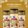 Three bottles of Mccormick Sugar Cookie Finishing Sugar, 3.39 Oz are displayed against a festive gold background with snowflakes to highlight the buttery vanilla sweetness of the limited edition holiday blend.