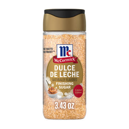 A clear plastic bottle of Mccormick Dulce De Leche Finishing Sugar, 3.43 Oz features a gold and black flip-top lid and a label decorated with snowflakes and a small bowl of caramel.