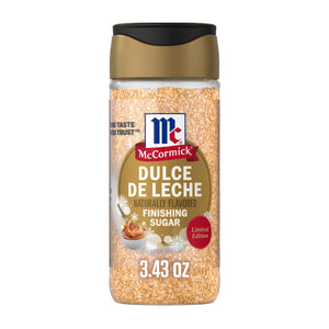 A clear plastic bottle of Mccormick Dulce De Leche Finishing Sugar, 3.43 Oz features a gold and black flip-top lid and a label decorated with snowflakes and a small bowl of caramel.