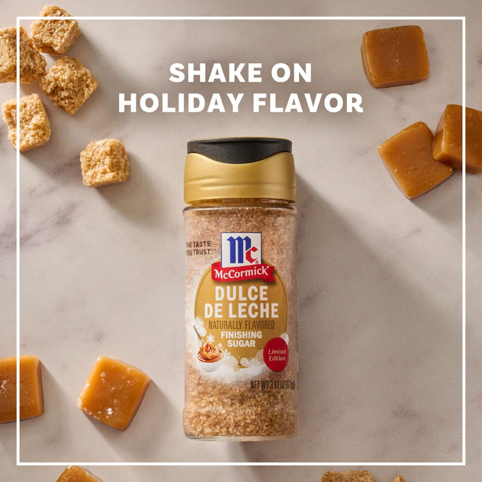 A bottle of Mccormick Dulce De Leche Finishing Sugar, 3.43 Oz is centered on a marble surface surrounded by brown sugar cubes and caramel squares under the text Shake On Holiday Flavor.