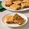 A plate of golden brown chocolate chip blondies is topped with a generous dusting of Mccormick Dulce De Leche Finishing Sugar, 3.43 Oz for a sweet and crunchy finish.