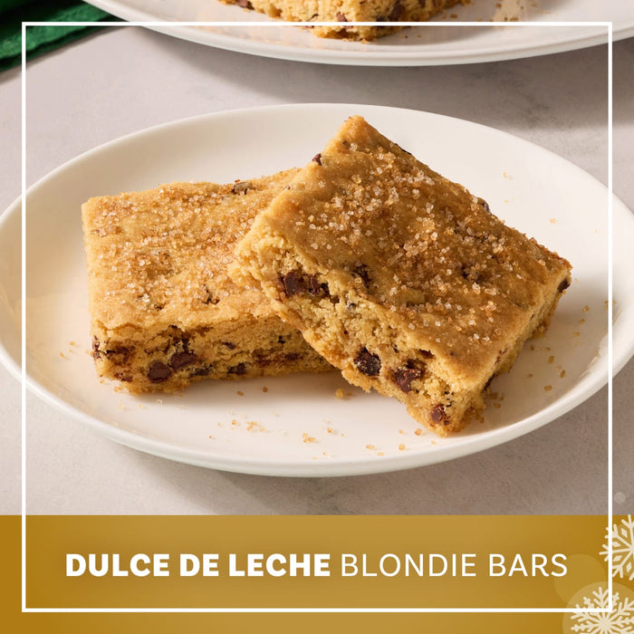 Two thick dulce de leche blondie bars with chocolate chips are served on a white plate and topped with a generous dusting of Mccormick Dulce De Leche Finishing Sugar, 3.43 Oz.