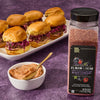 A jar of McCormick Flavor of the Year 2026 Sweet &amp; Smoky Black Currant Seasoning is displayed next to a bowl of sauce and a plate of sliders.
