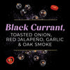 An artistic product shot featuring black currants, a sliced red jalapeño, and the text "Black Currant, Toasted Onion, Red Jalapeño, Garlic &amp; Oak Smoke."