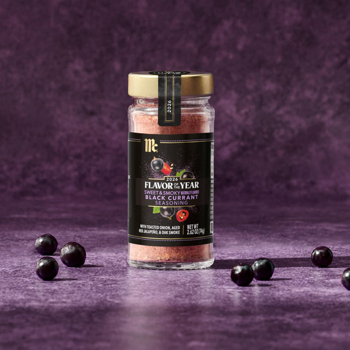 A jar of McCormick 2026 Flavor of the Year Sweet &amp; Smoky Naturally Flavored Black Currant Seasoning is surrounded by black currants.