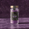 A jar of McCormick Flavor of the Year 2026 Black Currant Finishing Sugar sits on a textured purple surface.