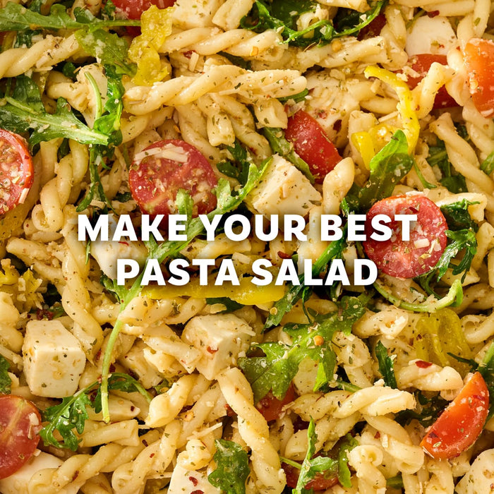A close-up of a pasta salad with tomatoes, cheese, and arugula, made with Mccormick Spicy Sicilian Style Seasoning, 1.62 Oz, is overlaid with the text, Make your best pasta salad.