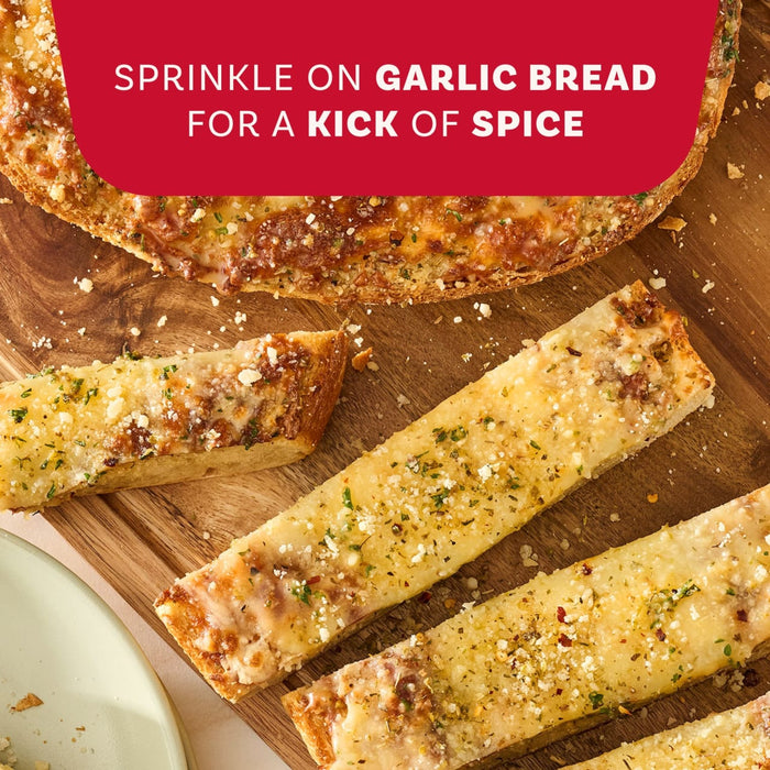 Cheesy garlic bread sticks on a wooden cutting board are shown as a serving suggestion after being sprinkled with Mccormick Spicy Sicilian Style Seasoning, 1.62 Oz for a kick of spice.