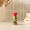 A bottle of Mccormick Savory Herb Parmesan Seasoning, 2.5 Oz, is displayed on a kitchen counter next to a utensil holder.