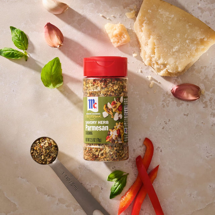 A bottle of Mccormick Savory Herb Parmesan Seasoning, 2.5 Oz is displayed in a top-down view with fresh ingredients like parmesan cheese, garlic, basil, and red pepper, along with a measuring spoon of the seasoning.