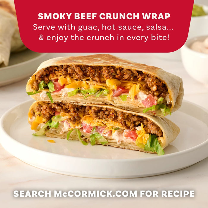 A delicious-looking Smoky Beef Crunch Wrap, a recipe that can be made using Mccormick Smoked Paprika And Garlic Seasoning, 3.12 Oz, is cut in half and stacked on a white plate to show the layers of beef, lettuce, and cheese inside.
