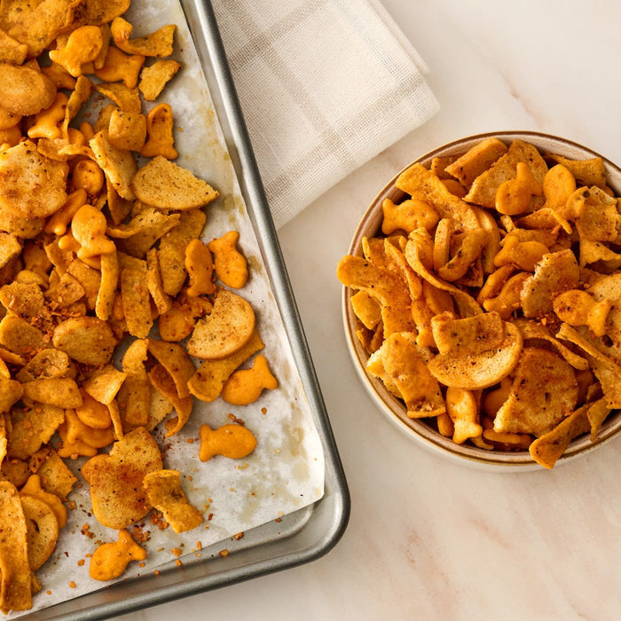 A delicious cracker snack mix on a baking sheet and in a bowl is generously seasoned with Mccormick Smoked Paprika And Garlic Seasoning, 3.12 Oz.
