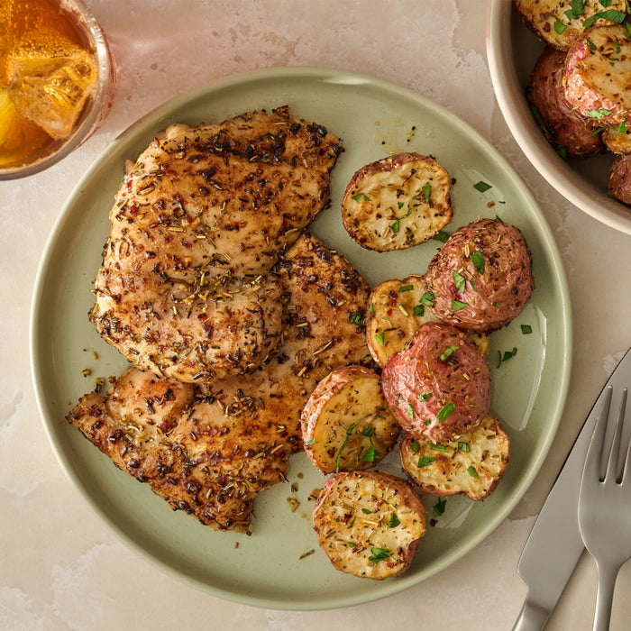 A delicious-looking meal of roasted chicken and red potatoes, generously seasoned with Mccormick Rosemary Lemon Seasoning, 2.75 Oz, is served on a green plate.