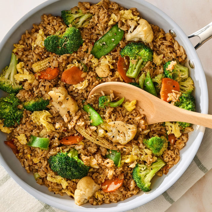 A light blue pan is filled with vegetable fried rice, made with broccoli, carrots, and egg, and seasoned with Mccormick Sesame Ginger Seasoning, 2.5 Oz.