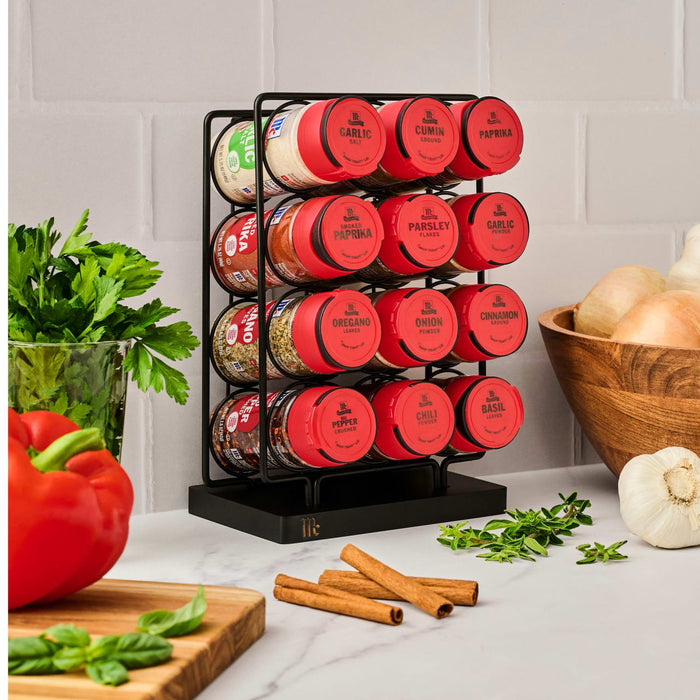 The image features a Mccormick Spice Rack Red Cap Black Metal 12 Ct, holding jars of garlic salt, cumin, paprika, smoked paprika, thyme, oregano, onion, cinnamon, crushed pepper, chili, and basil, displayed on a kitchen counter with fresh produce.