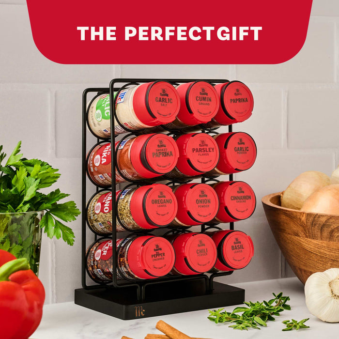 A Mccormick Spice Rack Red Cap Black Metal 12 Ct, filled with McCormick spices such as garlic salt, paprika, and basil, is presented on a kitchen counter with fresh herbs and cinnamon sticks, alongside the text The Perfect Gift on a red background.