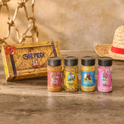 A collection of four limited-edition McCormick x Netflix One Piece seasonings, part of the Mccormick, 10.49 Oz product line, are displayed in front of their themed box on a wooden surface with a straw hat in the background.