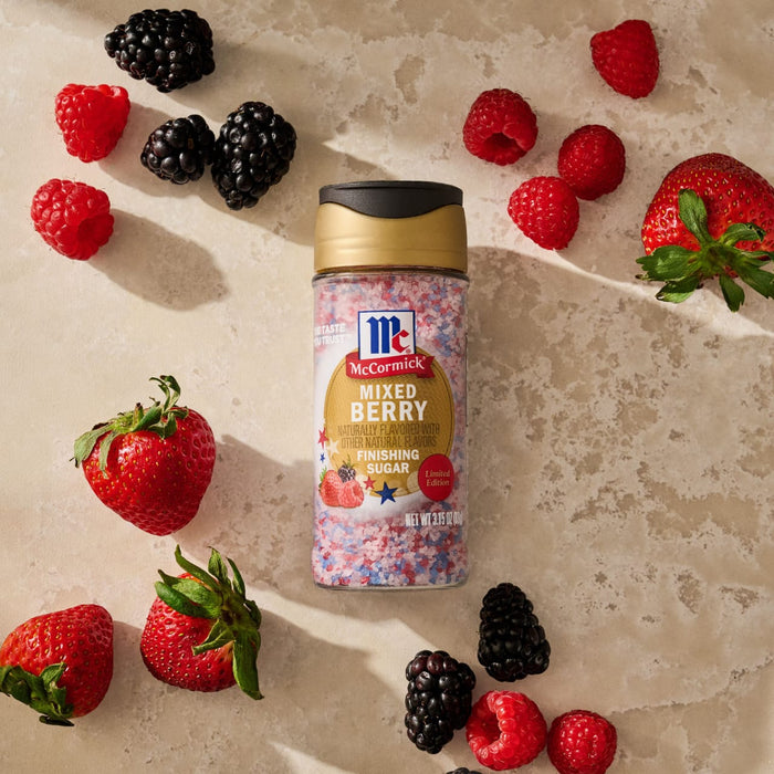 A bottle of Mc Mixed Berry Fin Sgr 72/6/3.15 Oz is centrally placed on a neutral surface, surrounded by fresh strawberries, raspberries, and blackberries to showcase its flavor profile.