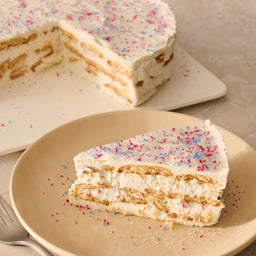 A slice of a layered icebox cake on a plate is topped with a festive garnish of Mc Mixed Berry Fin Sgr 72/6/3.15 Oz, with the rest of the cake in the background.