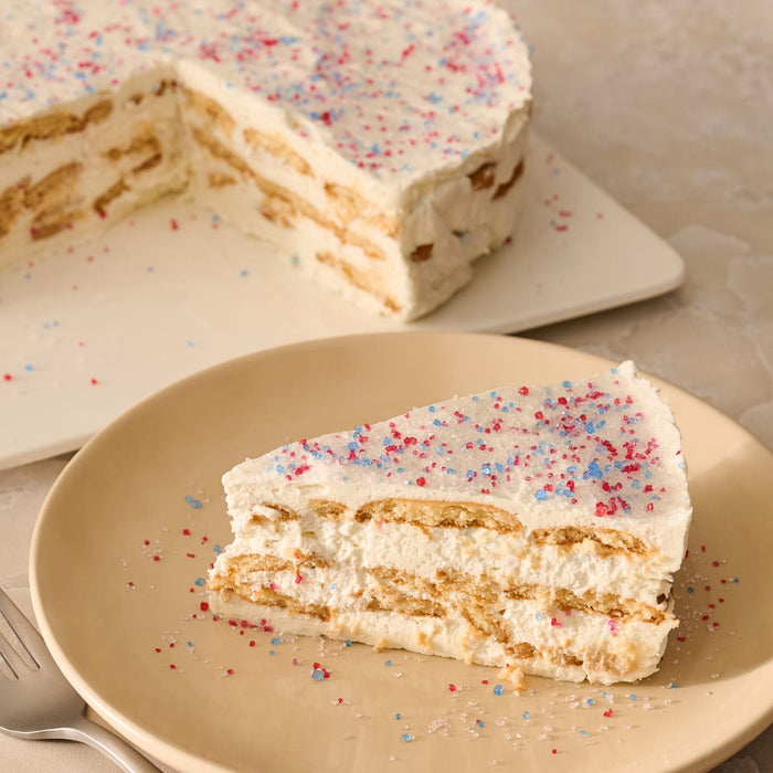 A slice of a layered icebox cake on a plate is topped with a festive garnish of Mc Mixed Berry Fin Sgr 72/6/3.15 Oz, with the rest of the cake in the background.
