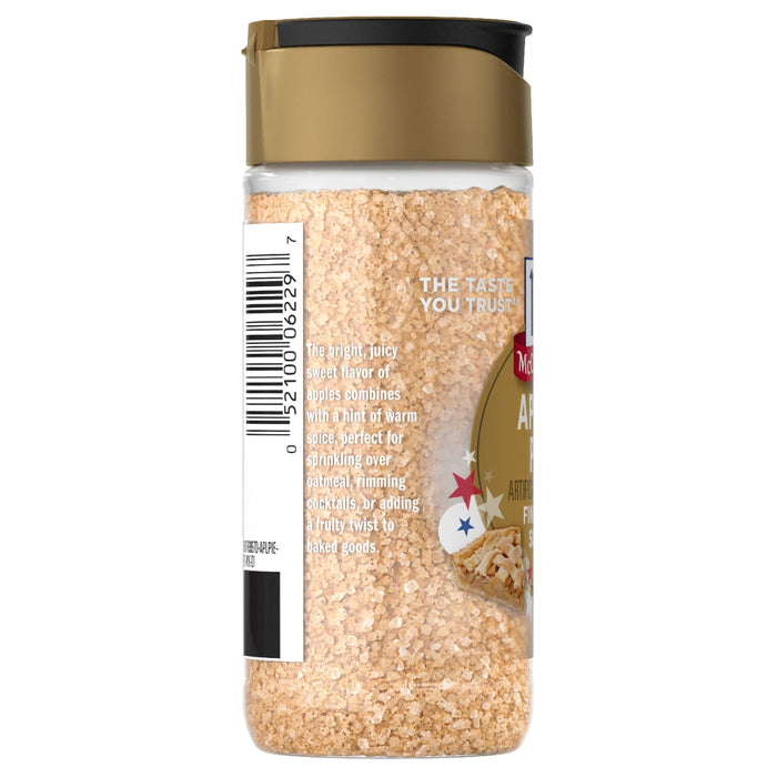 A side view of a bottle of Mccormick, 3.06 Oz apple pie flavored finishing sugar, showing the product's texture and descriptive label against a white background.