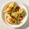A white plate holds three large dumplings smothered in a creamy sauce made with Mc Thai Gn Curry Mix and finished with a drizzle of chili oil and fresh herbs.