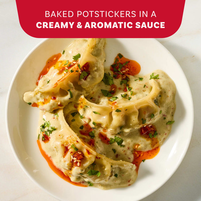 A white plate holds baked potstickers smothered in a creamy and aromatic sauce made with Mc Thai Gn Curry Mix and topped with chili oil and fresh herbs.