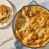 A golden brown chicken pot pie prepared with Mc Chkn Pot Pie Mix is served in a cast iron skillet alongside a portioned plate.
