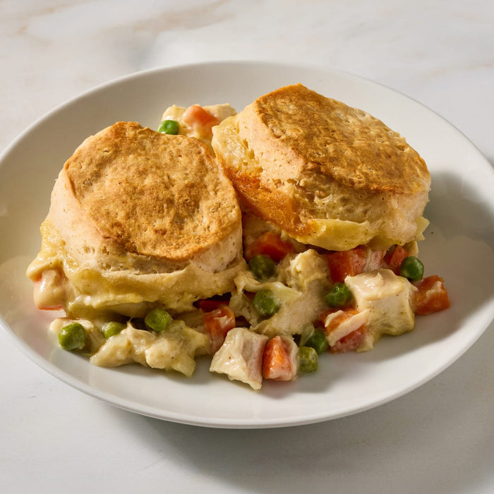 A white plate holds a serving of creamy chicken and vegetable filling topped with two golden brown biscuits made using Mc Chkn Pot Pie Mix.