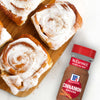 McCormick Cinnamon Baking Spice is featured next to freshly baked cinnamon rolls with white icing.
