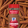 A jar of McCormick ground cinnamon is displayed against a background of cinnamon sticks.
