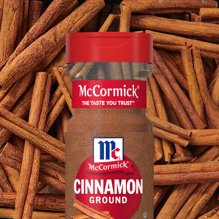 A jar of McCormick ground cinnamon is displayed against a background of cinnamon sticks.