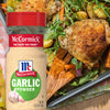 A bottle of McCormick Garlic Powder next to a baking dish of roasted chicken potatoes carrots and arugula.