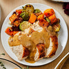 ['A plate of roasted turkey with gravy, Brussels sprouts, and butternut squash.']