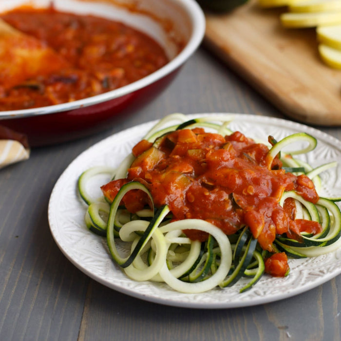 ['Zucchini noodles topped with a red sauce.']