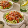 A bowl of pasta with a red sauce and green peppers, a red pot with the same pasta and sauce, and a McCormick Thick &amp; Zesty Spaghetti packet.