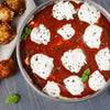 ['A close-up of a dish of lasagna with ricotta cheese and marinara sauce.']