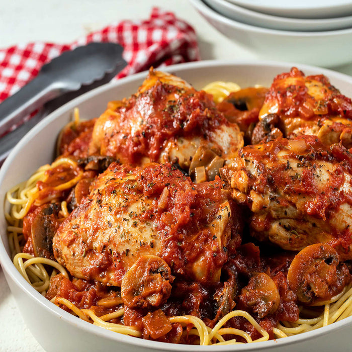 ['A bowl of spaghetti with chicken and mushrooms in a tomato sauce.']