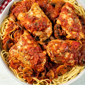 ['A bowl of spaghetti with chicken and mushrooms in a tomato sauce.']