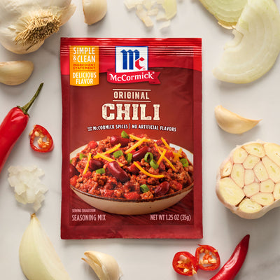 McCormick Original Chili seasoning mix packet surrounded by chili ingredients on a light background