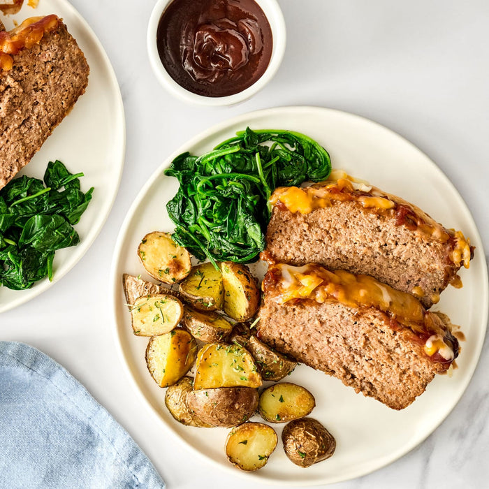 A plate of meatloaf with potatoes and spinach.