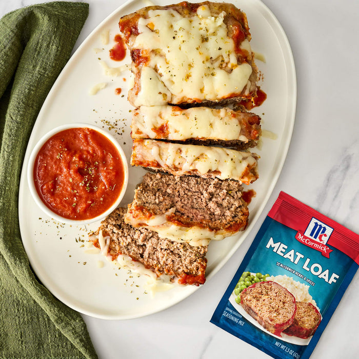 A plate of sliced meatloaf topped with marinara sauce and mozzarella cheese with a McCormick Meatloaf seasoning packet.