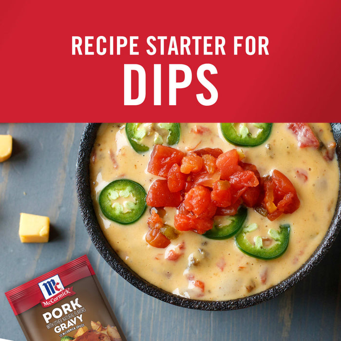 ['A bowl of cheesy dip with diced tomatoes and jalapenos, with a McCormick Pork Gravy packet in the foreground.']