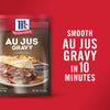['A package of McCormick Au Jus Gravy mix with a sandwich and gravy on a plate.']