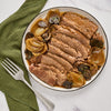 ['A plate of sliced roast beef with onions and mushrooms.']