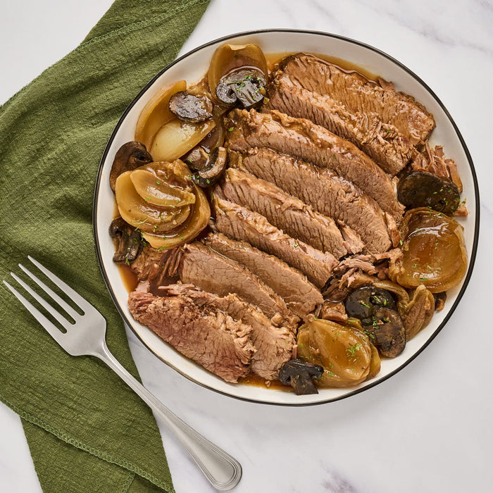 ['A plate of sliced roast beef with onions and mushrooms.']